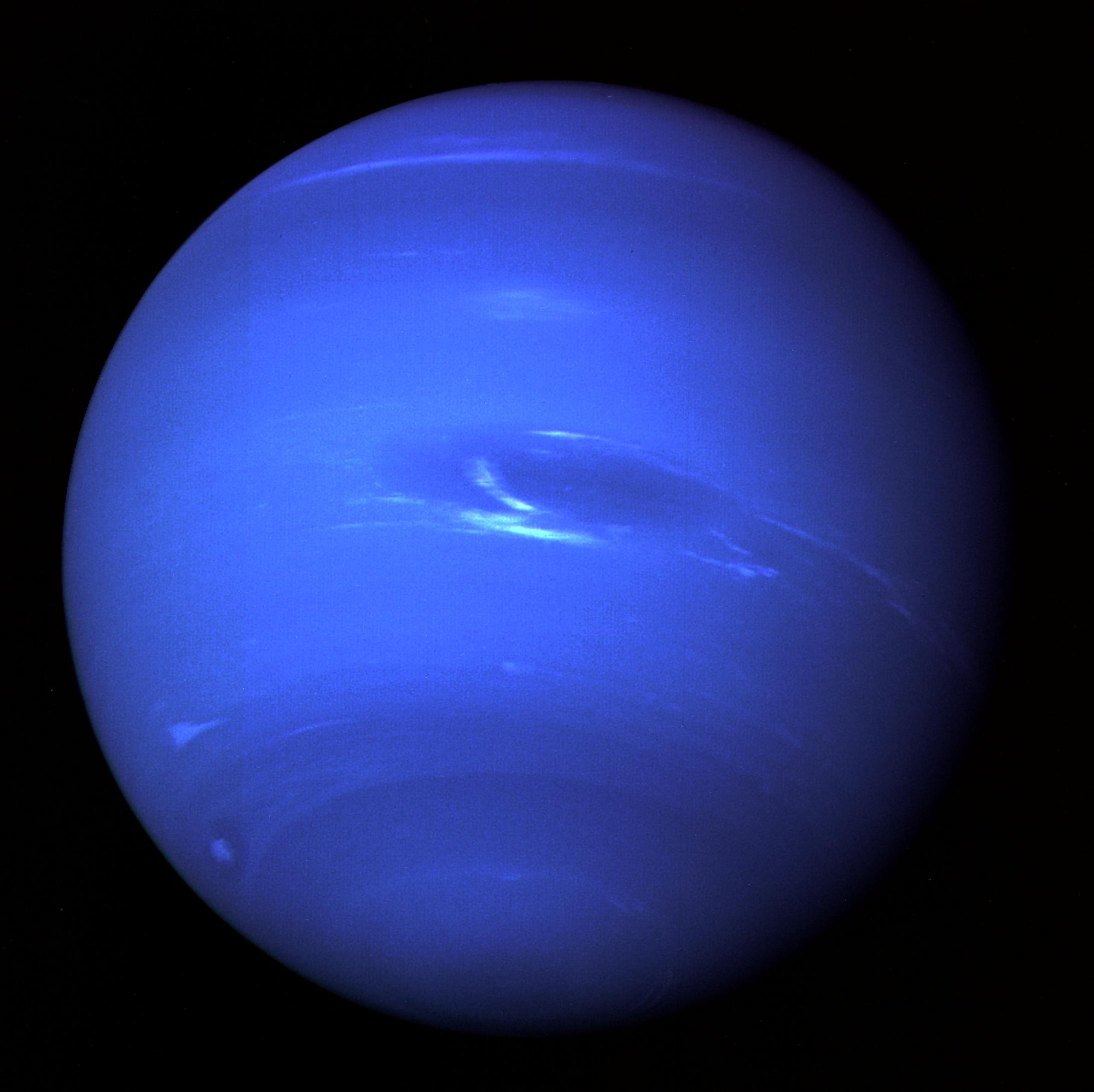 Voyager 2’s view of Neptune shows the Great Dark Spot and bright methane-ice clouds. Image processing enhances the planet’s blue color.